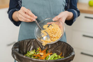 Compost the kitchen waste, recycling, organic meal asian young household woman use spoon scraping, throwing food leftovers into garbage, trash bin from vegetable. Environmentally responsible, ecology.
