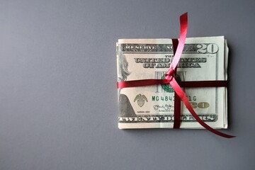 Cash dollar money in red ribbon on gray background with copy space - concept of money saving budget...