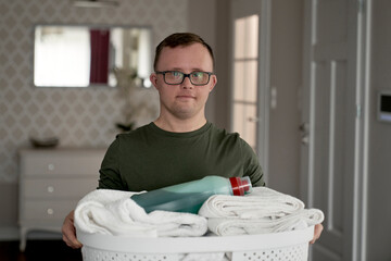 Portrait of caucasian adult caucasian man with down syndrome with laundry basket