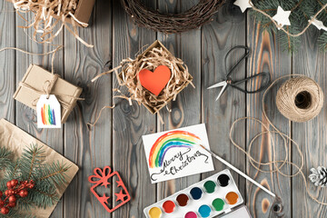 Watercolor rainbow postcard and handmade gift box in festive package, top view. Spruce branches and...