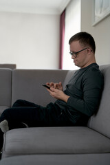 Man with down syndrome using mobile phone at home while sitting on sofa