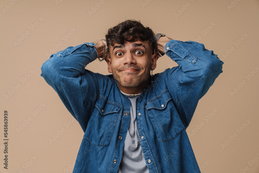 Wall mural Young handsome stylish man with pursed lips holding his head