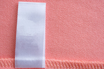 Fototapeta premium Blank white laundry care clothes label on pink fabric texture background
