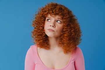 White ginger woman with curly hair grimacing and looking aside