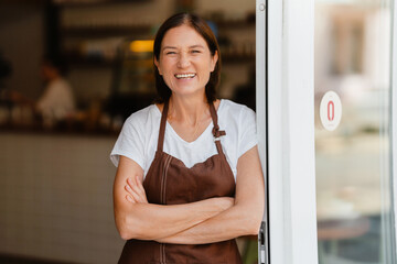 White mature barista woman smiling while working in cafe