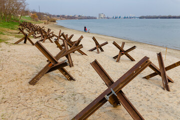 Metallic military obstacles, anti tank hedgehoges on bank. Constructions protecting freedom, independence of Ukraine 2022 © aseiryk