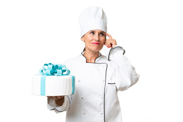 Middle-aged chef caucasian woman with a big cake over isolated background having doubts and with confuse face expression