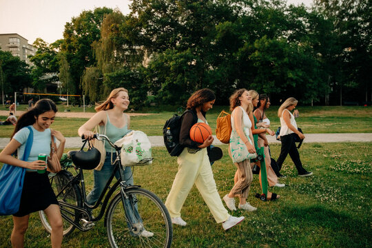 Smiling teenage girls walking together at park during sunset
