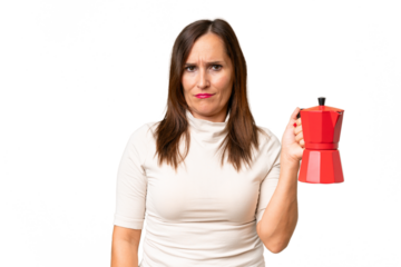 Middle-aged caucasian woman holding coffee pot over isolated background with sad expression