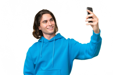 Young handsome man isolated on green chroma background making a selfie with mobile phone