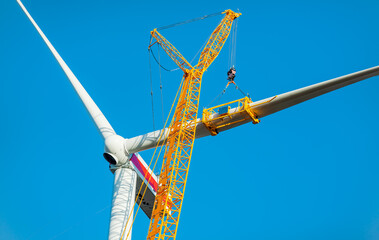 Construction work of wind turbine. crane is holding, grabing a blade of a wind turbine. Building...
