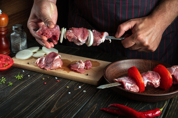 Professional chef pricks raw meat on a skewer. The process of cooking meat shish kebab in the kitchen by the hands of a cook