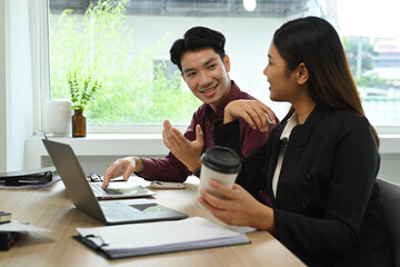 Obraz premium Smiling Asian businessman explaining new project and discussing corporate business plan with his colleague