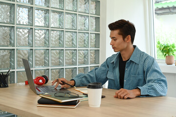 Handsome asian male freelancer in blue shirt working online in laptop computer