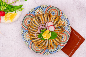 Fried anchovy, delicious Turkish Blacksea European anchovy. Garnished with lemon, turnip, onion and arugula