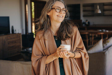 Happy senior woman smiling while holding a cup of tea - Powered by Adobe