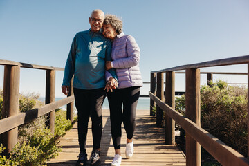 Elderly couple taking a walk along a foot bridge at the beach