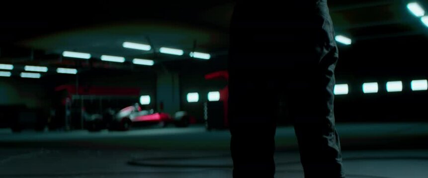 Silhouette of a racing pilot entering the pitlane garage with sports car prepared for a race