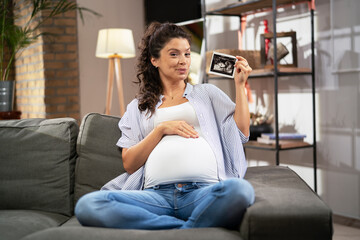 Pregnant woman with ultrasound photo. Beautiful pregnant woman enjoy at home