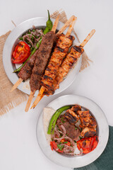 Delicious traditional Adana Kebab made with minced lamb and chicken shish kebab spices, served with lavash, ayran Turkish buttermilk and roasted pepper tomato and red onion top view flat lay photo 
