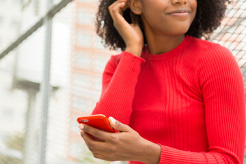 cropped unrecognizable young woman with mobile phone in hand looking sideways