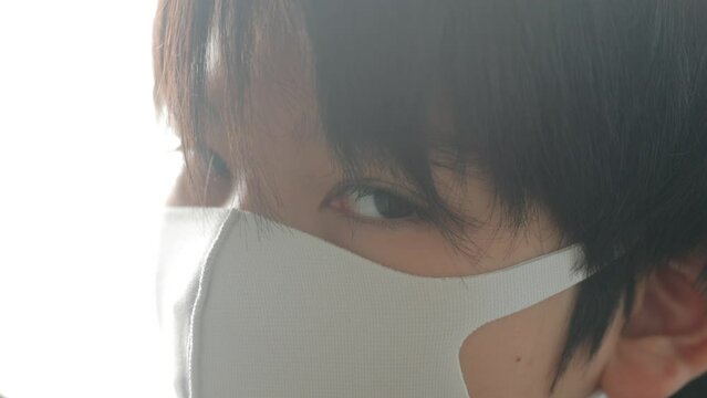 Teenage boy glaring the camera to show his frustration to wear a mask all the time.