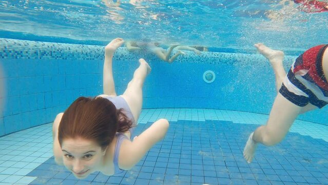 Cute little girl and father swimming underwater in a pool