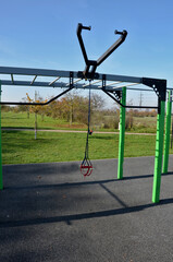 itness sports fields with stainless steel tools resemble torture tools with chains and handles. soft rubber surface sports ground outdoor gym. man holds a pulley and strengthens muscles