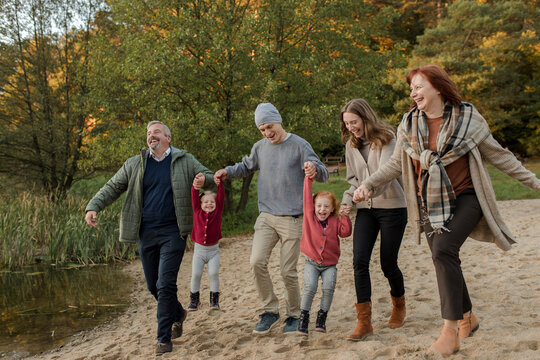 Playful family spending leisure time with each other walking on sand - Powered by Adobe