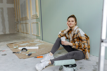 Thoughtful woman with disposable coffee cup sitting on floor at home