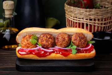 Meatball sandwich with tomato, onion, barbecue sauce.