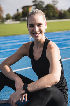 Smiling young sportswoman on running track