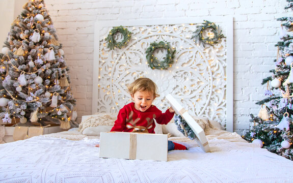 Child Open Christmas Gifts Under The Tree. Selective Focus.