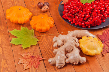 Still life with pumpkin- patison. Red viburnum berry, cranberry.Chicory root.Nuts. Autumn maple leaves.On a wooden background.meal.Thanksgiving day.the concept of fresh vegetables..place for text	