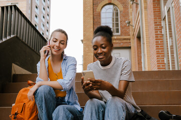 Young multinational girls smiling and using cellphones together