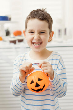 Happy boy holding jack o lantern at home