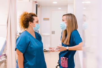Nurses wearing masks talking with each other at hospital