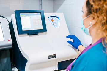Mature nurse analyzing blood sample through machinery at laboratory