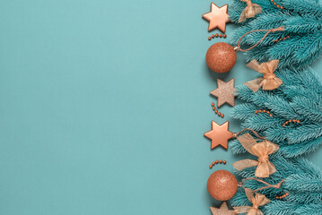 Christmas border with decorative fir branches and golden ornaments on a turquoise pastel...