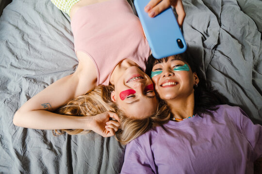 Two multiracial girls in eye patches taking selfie on mobile phone