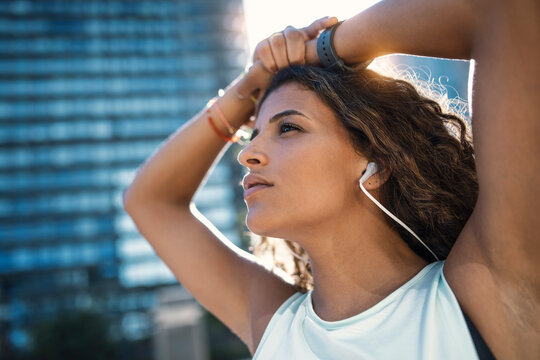 Young woman wearing headphones standing on sunny day