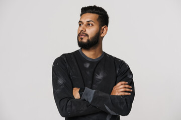 Young indian man looking aside while posing with arms crossed