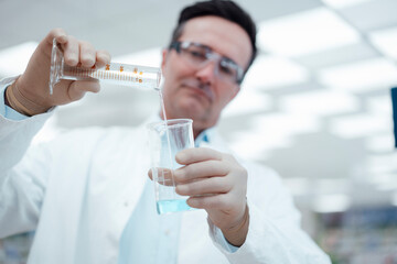 Chemist pouring solution from test tube to flask in laboratory