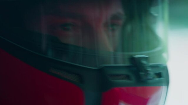 ECU Portrait of sports car driver in protective helmet racing on a speedway. Fast speed, motorsport. Daytime shot