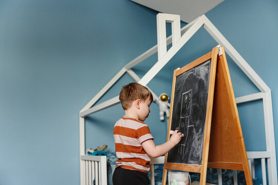 Boy writing on chalkboard in bedroom at home