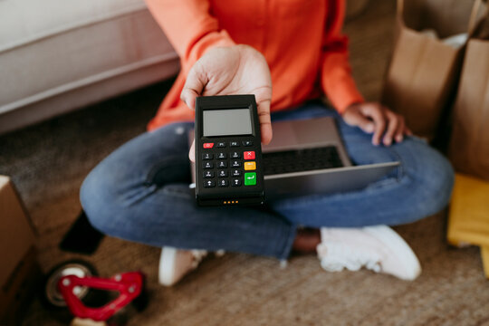 Hand of businesswoman holding credit card reader at home office