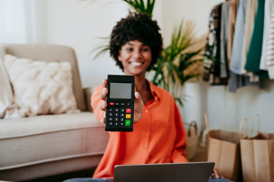 Happy businesswoman showing credit card reader at home office