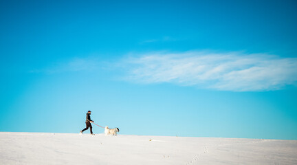 man and his happy white dog enjoying winter snow outdoors on sunny day
