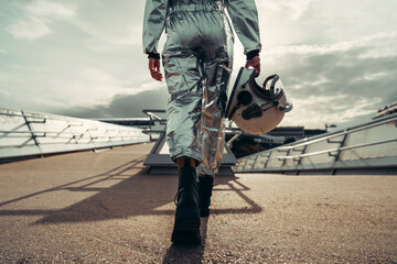 Hand of astronaut holding space helmet walking on footpath