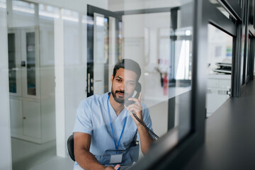 Young multiracial doctor sitting at reception and calling.